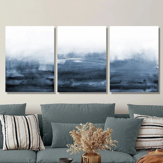 Three abstract wall art pieces above a sofa with decorative pillows and a vase.