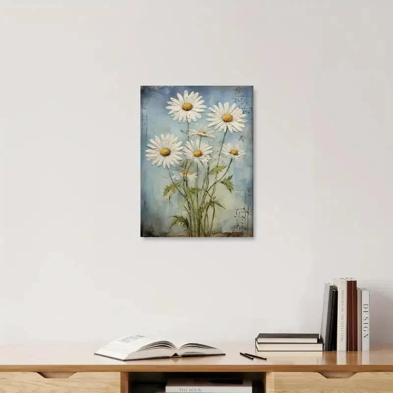 Framed artwork of daisies on a wall above a wooden shelf with books.