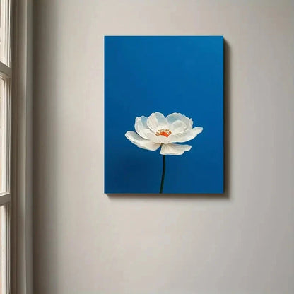 Canvas print of a white flower on a blue background hanging on a wall.