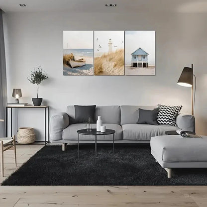 Modern living room with a gray sectional sofa, black rug, and wall art depicting beach scenes.