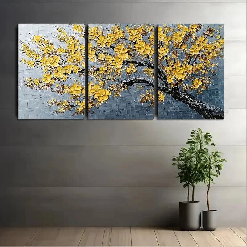 Three-panel wall art of a yellow floral tree against a gray background, with two potted plants on a wooden floor.