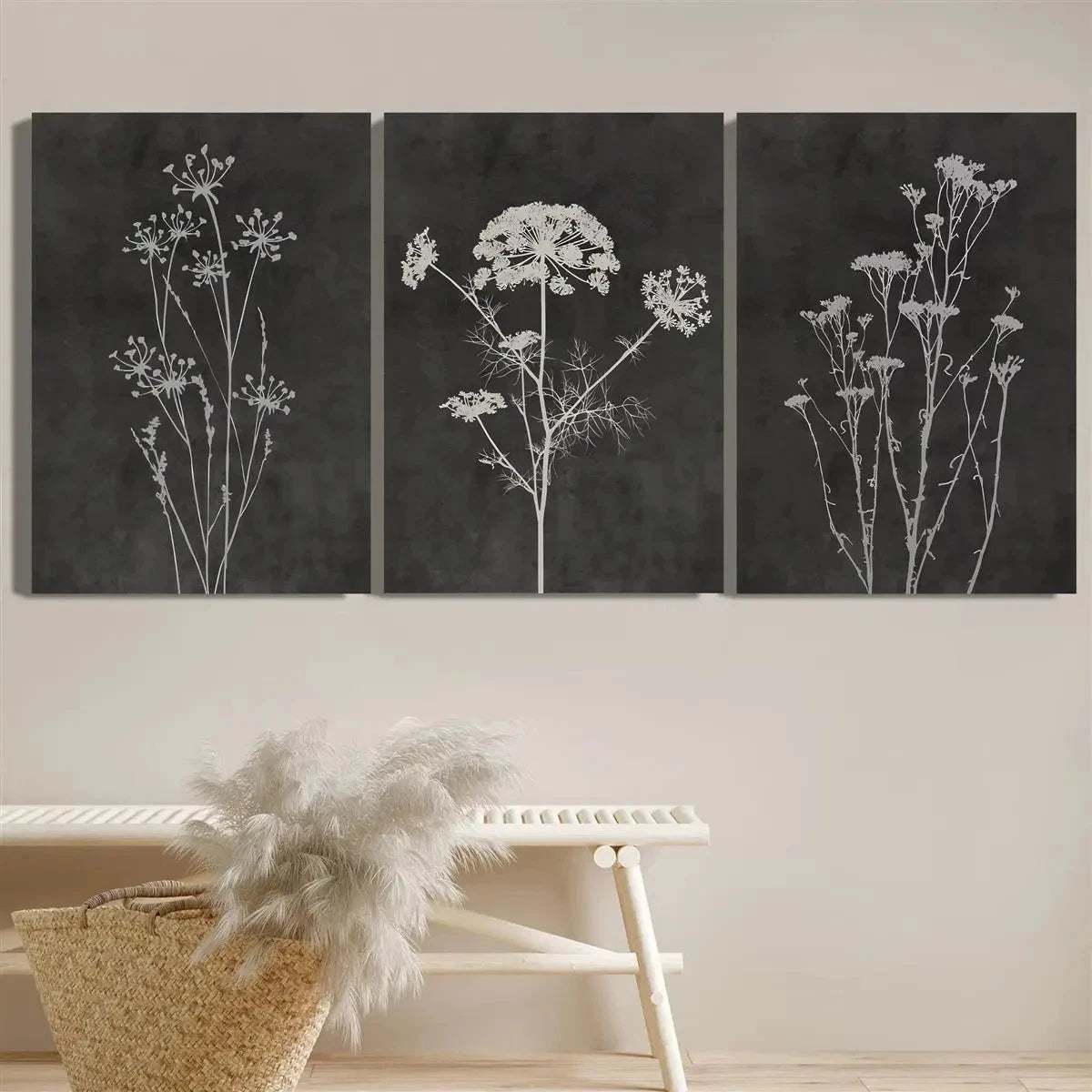 Three black and white floral artworks on a wall above a bench.