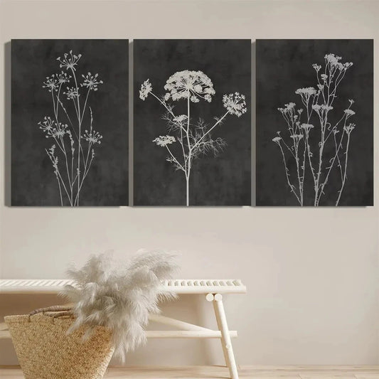 Three black and white floral artworks on a wall above a bench.