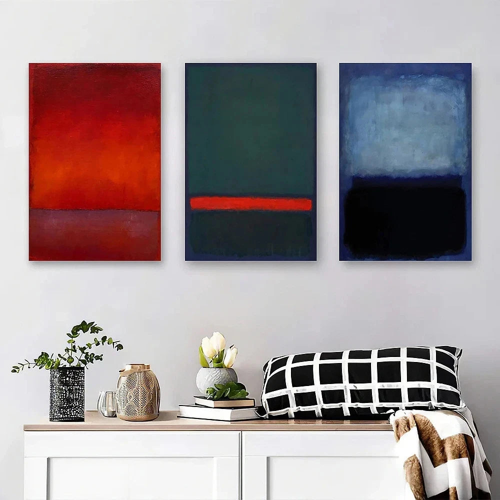 Three abstract paintings on a wall above a white cabinet with decorative items.