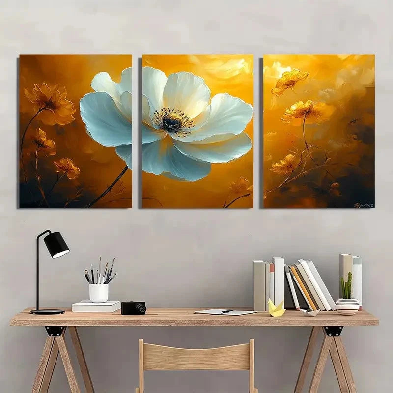 Three-panel floral artwork above a wooden desk with books and a lamp.