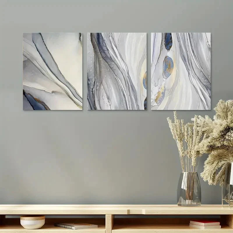 Three abstract wall art pieces on a gray wall above a wooden shelf with decorative items.