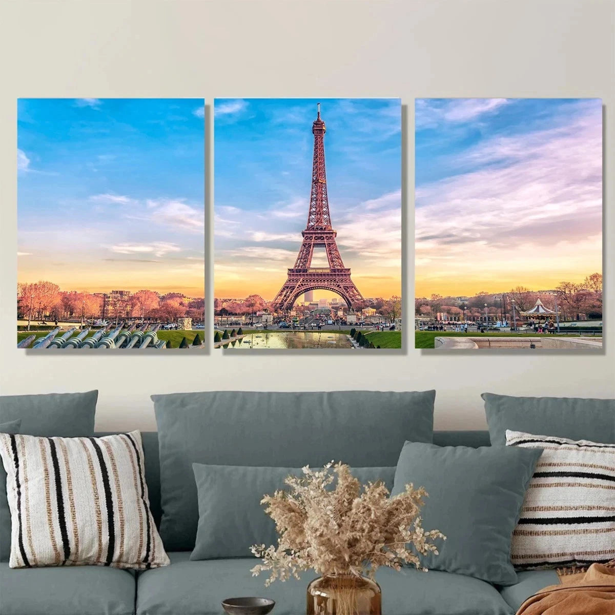 Three-panel wall art of the Eiffel Tower with a couch and decorative pillows in the foreground.