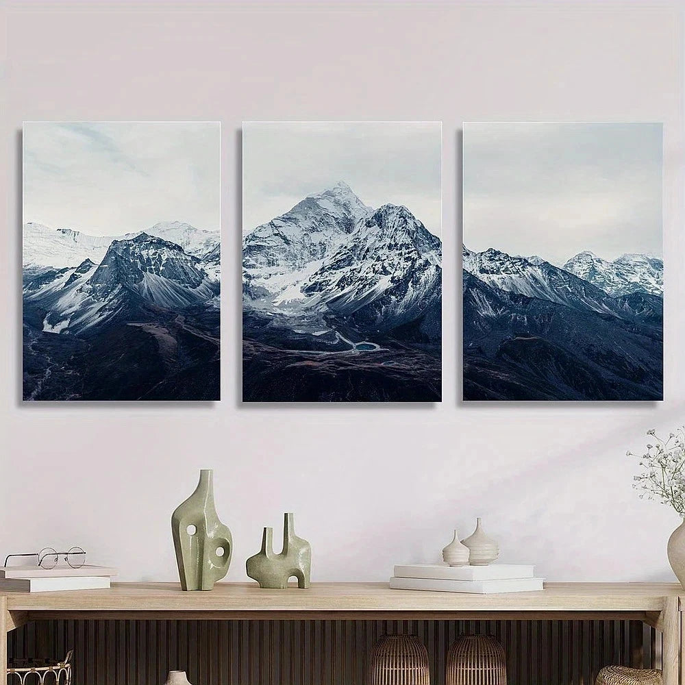 Three framed mountain landscape artworks on a wall above a wooden console table.