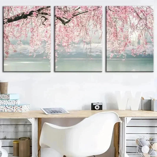 Three-panel wall art of cherry blossom branches with pink flowers above a desk.