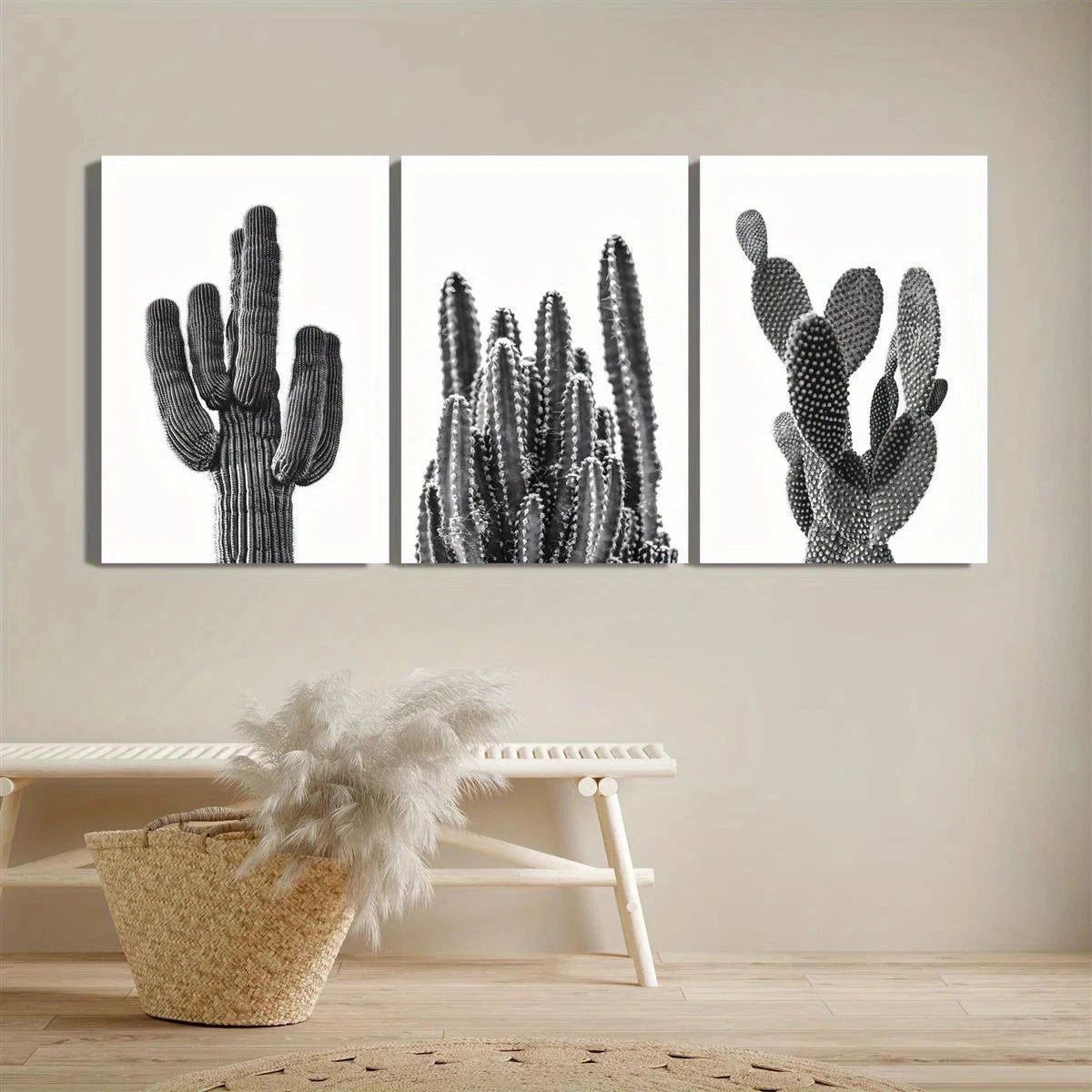 Three black and white cactus artworks on a beige wall with a decorative basket and plant below.