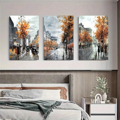 Three framed artworks depicting a city street scene with autumn trees above a bed.