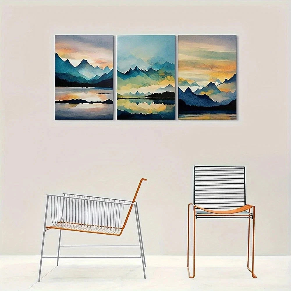 Three-panel wall art of a mountain landscape with two chairs below.