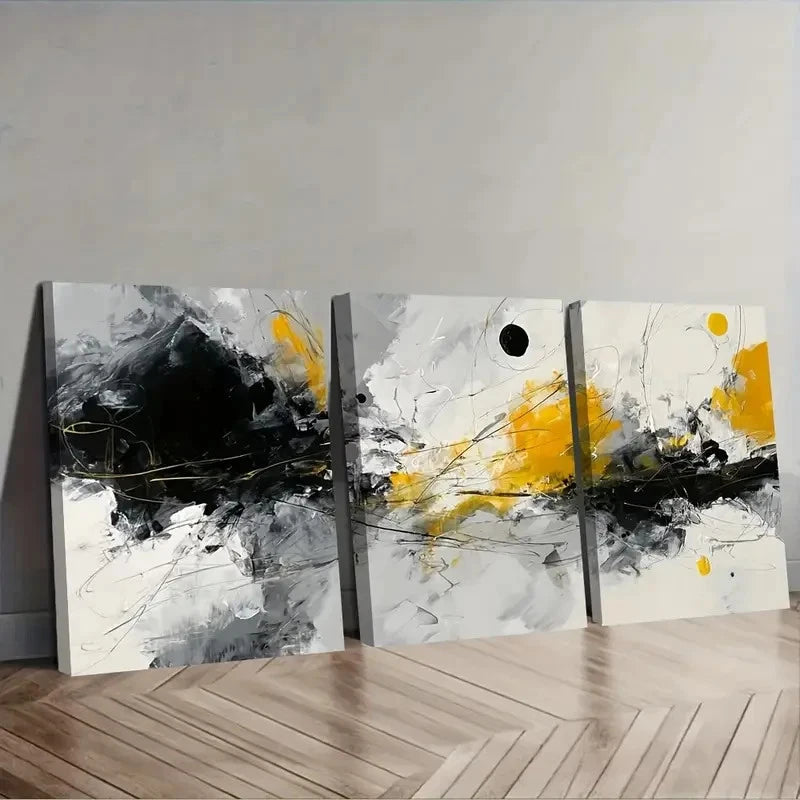 Set of three abstract paintings with yellow and black elements on a gray wall.