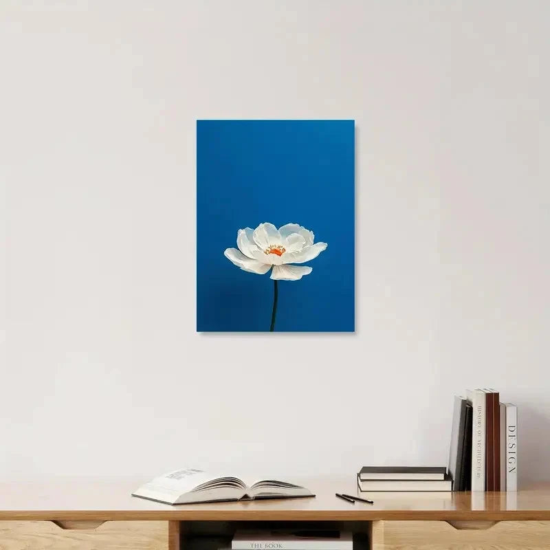 White flower painting on a blue background above a wooden shelf with books.