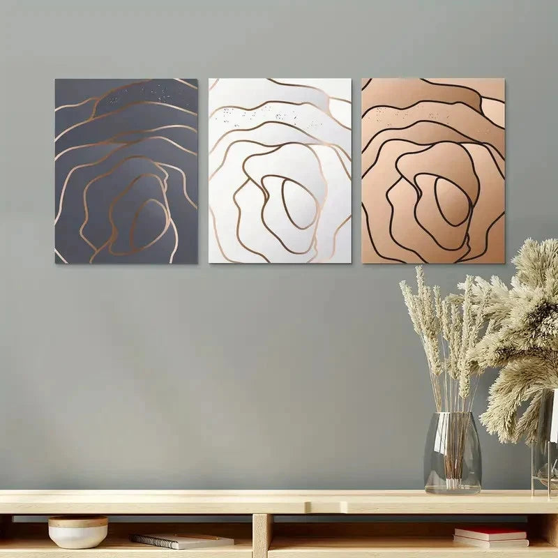 Three abstract wall art pieces on a gray wall above a wooden shelf with decorative items.