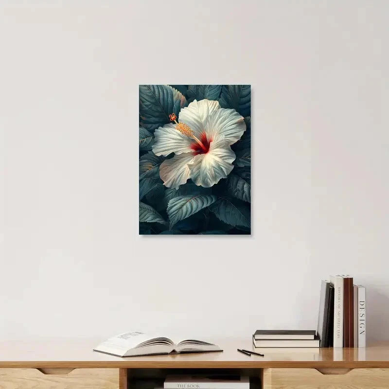 Framed artwork of a white flower with green leaves on a wall above a wooden shelf with books.