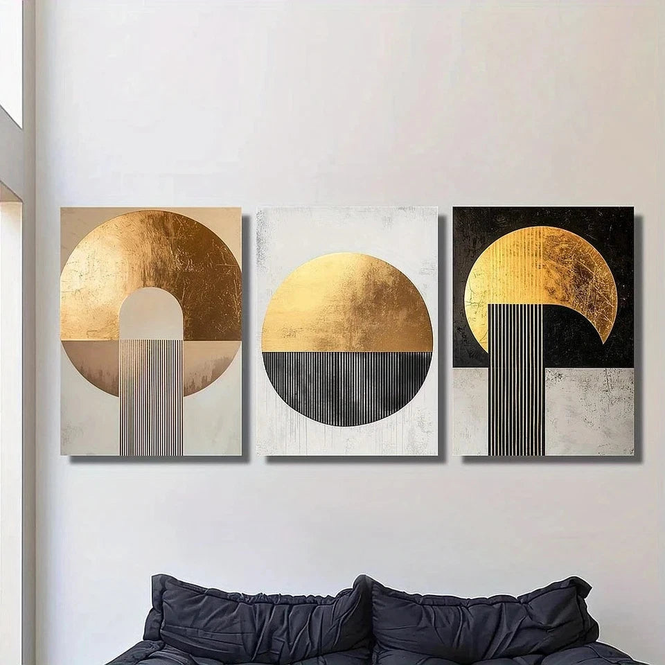 Three abstract wall art pieces with gold and black designs on a white wall above a sofa.