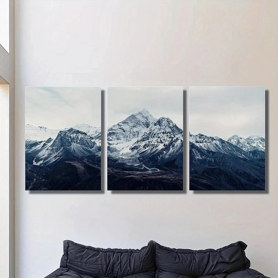 Three-panel wall art of a mountain landscape on a white wall above a sofa.