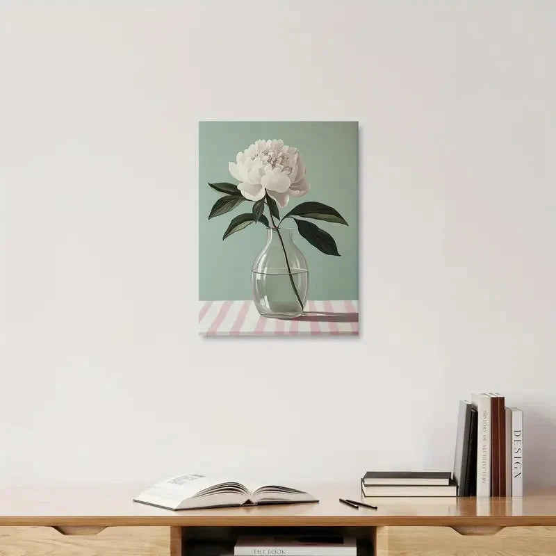 Canvas print of a flower in a vase on a striped tablecloth, hanging above a wooden shelf with books.