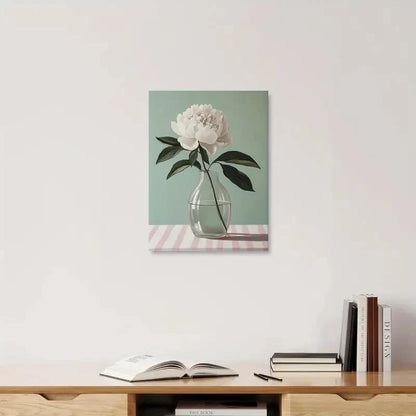 Canvas print of a flower in a vase on a striped tablecloth, hanging above a wooden shelf with books.