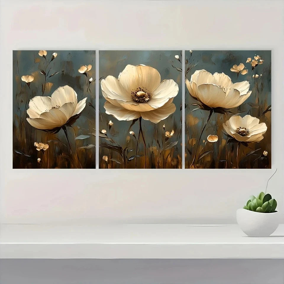 Triptych painting of beige flowers on a wall with a white shelf and small plant.