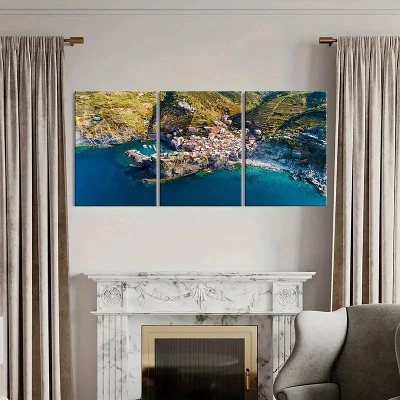 Triptych wall art of a coastal village above a fireplace with curtains on either side.