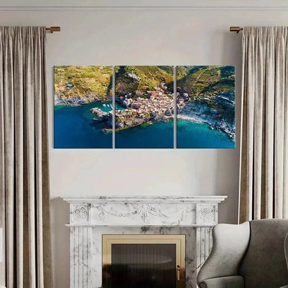 Triptych wall art of a coastal village above a fireplace with curtains on either side.