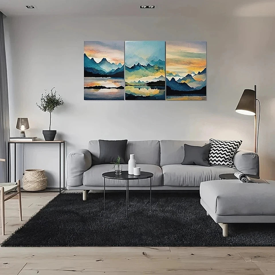 Modern living room with a gray sectional sofa, coffee table, and wall art depicting mountains and water.