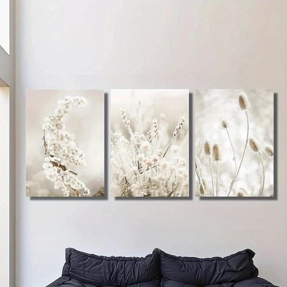 Three floral wall art pieces on a white wall above a black sofa.