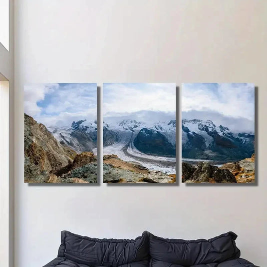 Three-panel canvas print of a mountain landscape hanging on a wall above a sofa.